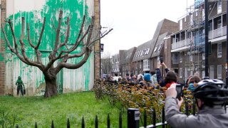 People look at a new Banksy painting on a wall in London, Monday, March 18, 2024.