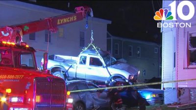 Pickup truck crashes into Brockton home, lands on cars