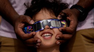 FILE – Viewers use special glasses to watch from San Antonio, as the moon moves in front of the sun during an annular solar eclipse, or ring of fire, Oct. 14, 2023. The total solar eclipse on April 8, 2024 may be weeks away but businesses are ready for the celestial event with oodles of special eclipse glasses for sale, along with T-shirts and other souvenirs.