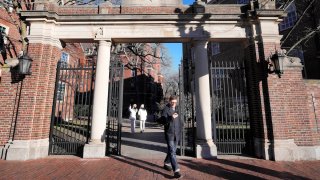 FILE – A passer-by walks through a gate to the Harvard University campus, Jan. 2, 2024, in Cambridge, Mass.