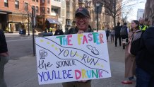 Brad Lew holding a sign saying, "The faster you run, the sooner you'll be drunk," to support his daughter, Sydney, while during the Boston Marathon on Monday, April 15, 2024.