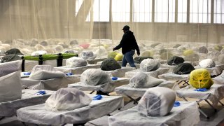 A worker walks through the over 300 Army cots on the gym floor as State and local officials toured the Melnea A. Cass Recreational Complex. The facility will be housing over 300 migrants.