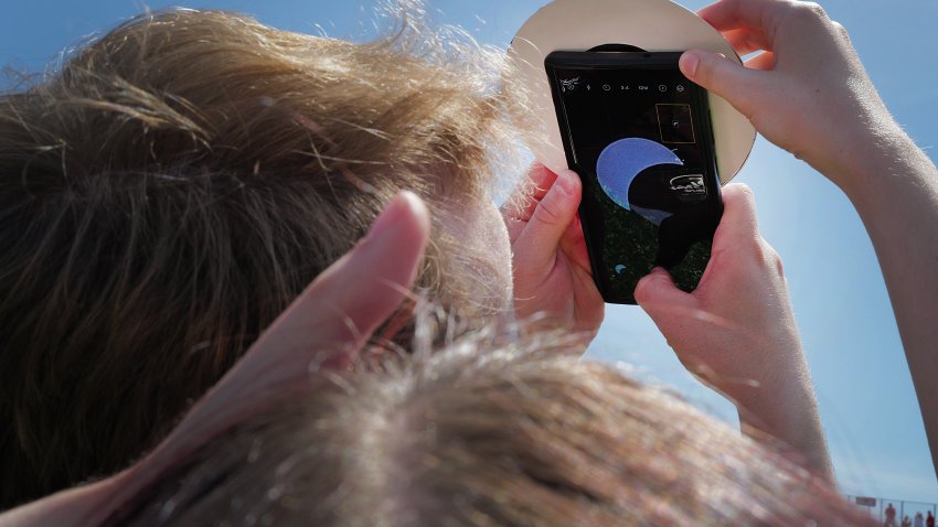 Person holding phone to eclipse