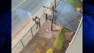 A man in a face covering throwing a pipe bomb at the entrance of the Satanic Temple in Salem, Massachusetts, early Monday, April 8, 2024, as seen in surveillance video released by federal prosecutors.