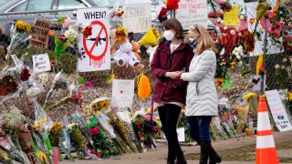 FILE – Mourners walk along the temporary fence put up around the parking lot of a King Soopers grocery store where a mass shooting took place earlier in the week, Thursday, March 25, 2021, in Boulder, Colo.