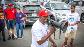 In this February file photo, Paul Mbimeh of Brockton takes to the megaphone as Uber and Lyft drivers protest to demand union rights and higher wages at the Massachusetts State House.