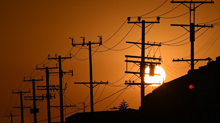 The sun sets behind power lines near homes during a heat wave in Los Angeles, Sept. 6, 2022.