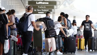 Travelers walk with their luggage outside the international terminal at Los Angeles International Airport (LAX) ahead of the July 4th holiday travel period on June 25, 2024 in Los Angeles, California. 