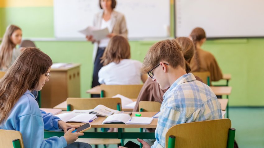 Teenagers using phones during lesson