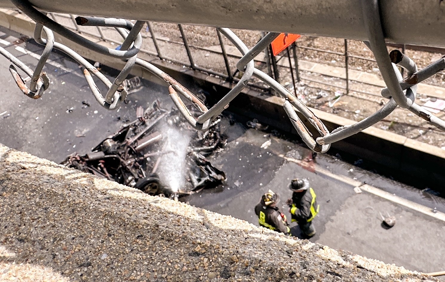 Firefighters spraying the charred wreckage of a vehicle in Boston by Widett Circle on Wednesday, June 5, 2024.