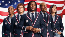 A group of people pose for a photo with the American flag in the background.