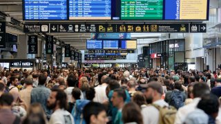 Passengers gather around the departure boards at the Gare Montparnasse train station in Paris on July 26, 2024 as France’s high-speed rail network was hit by malicious acts disrupting the transport system hours before the opening ceremony of the Paris 2024 Olympic Games. 