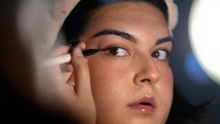 Daniella López White, of Hawaii, uses a mirror while applying makeup