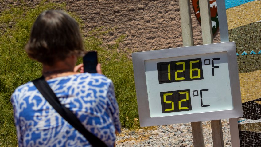 A woman takes a photo of a thermostat reading 126 degrees Fahrenheit and 52 degrees Celsius at the Furnace Creak Visitors Center in Death Valley National Park, Calif., Sunday, July 7, 2024. Forecasters say a heat wave could break previous records across the U.S. including at Death Valley.