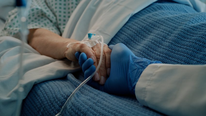 File. Hospital, holding hands and bed with doctor, support and care together in a clinic after surgery.