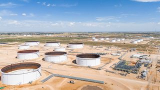 In an aerial view, oil storage containers are seen at the Enterprise Crude Pipeline operations facility on June 27, 2024 in Midland, Texas.