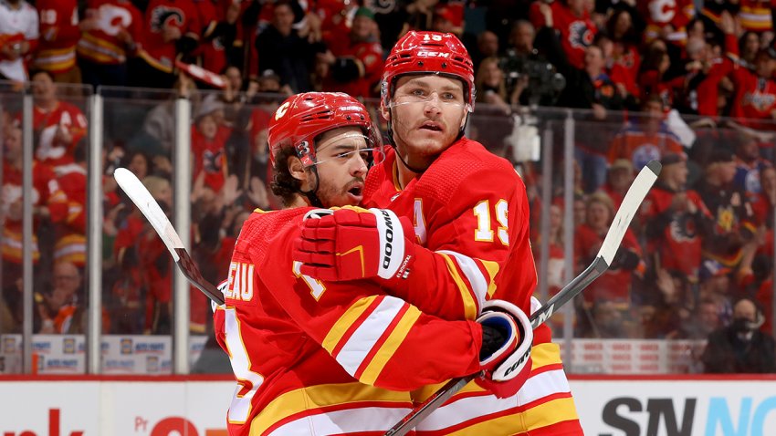 CALGARY, ALBERTA – MARCH 26: Johnny Gaudreau #13, Matthew Tkachuk #19 and teammates of the Calgary Flames celebrate a goal against the Edmonton Oilers at Scotiabank Saddledome on March 26, 2022 in Calgary, Alberta. (Photo by Gerry Thomas/NHLI via Getty Images)