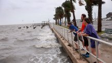 CEDAR KEY, FLORIDA - AUGUST 04: Shon Whitwood (C) and Leah Whitwood (R) stand in the wind and rain before the possible arrival of Tropical Storm Debby, which is strengthening as it moves through the Gulf of Mexico on August 04, 2024 in Cedar Key, Florida. Forecasters say Tropical Storm Debby could become a hurricane as soon as Sunday evening, bringing rain storms and high winds along Florida’s west coast. (Photo by Joe Raedle/Getty Images)