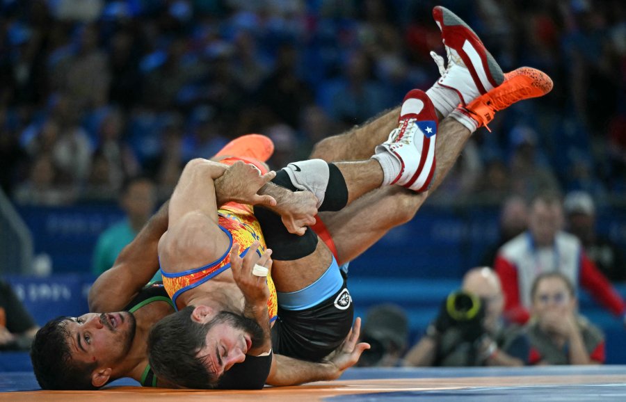 Moldova's Maxim Sacultan wrestles Puerto Rico's Sebastian C Rivera (blue) in their men's freestyle 65kg wrestling repechage match at the Champ-de-Mars Arena during the Paris 2024 Olympic Games, in Paris on August 11, 2024