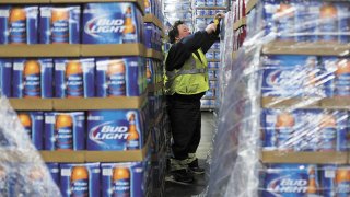 An employee cuts the plastic wrap off of pallets of Budweiser and Bud Light inside the Anheuser-Busch Louisville Sales and Service Center.