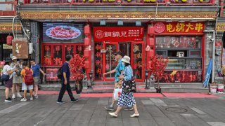 People walk along the Huguosi street, Xicheng district, a dedicated food street in Beijing on August 23, 2024. 