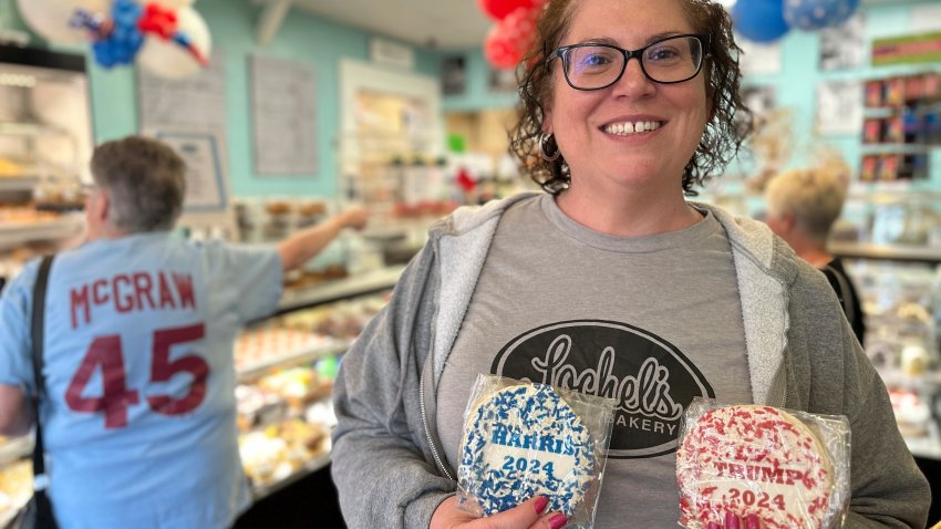 Bakery owner Kathleen Lochel holds sugar cookies, one with blue and white sprinkles and a Harris 2024 label on it and the other, with red and white sprinkles and a Trump 2024 label on it in Lochel Bakery, Tuesday, Sept. 24, 2024, in Hatboro, a suburb of Philadelphia. (AP Photo/Tassanee Vejpongsa)