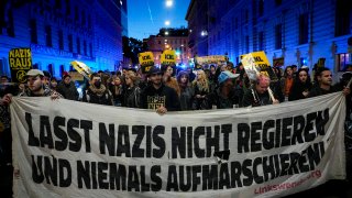 Anti right wing protesters shout slogans holding a banner that reads "Don't let Nazis rule and never let them march"