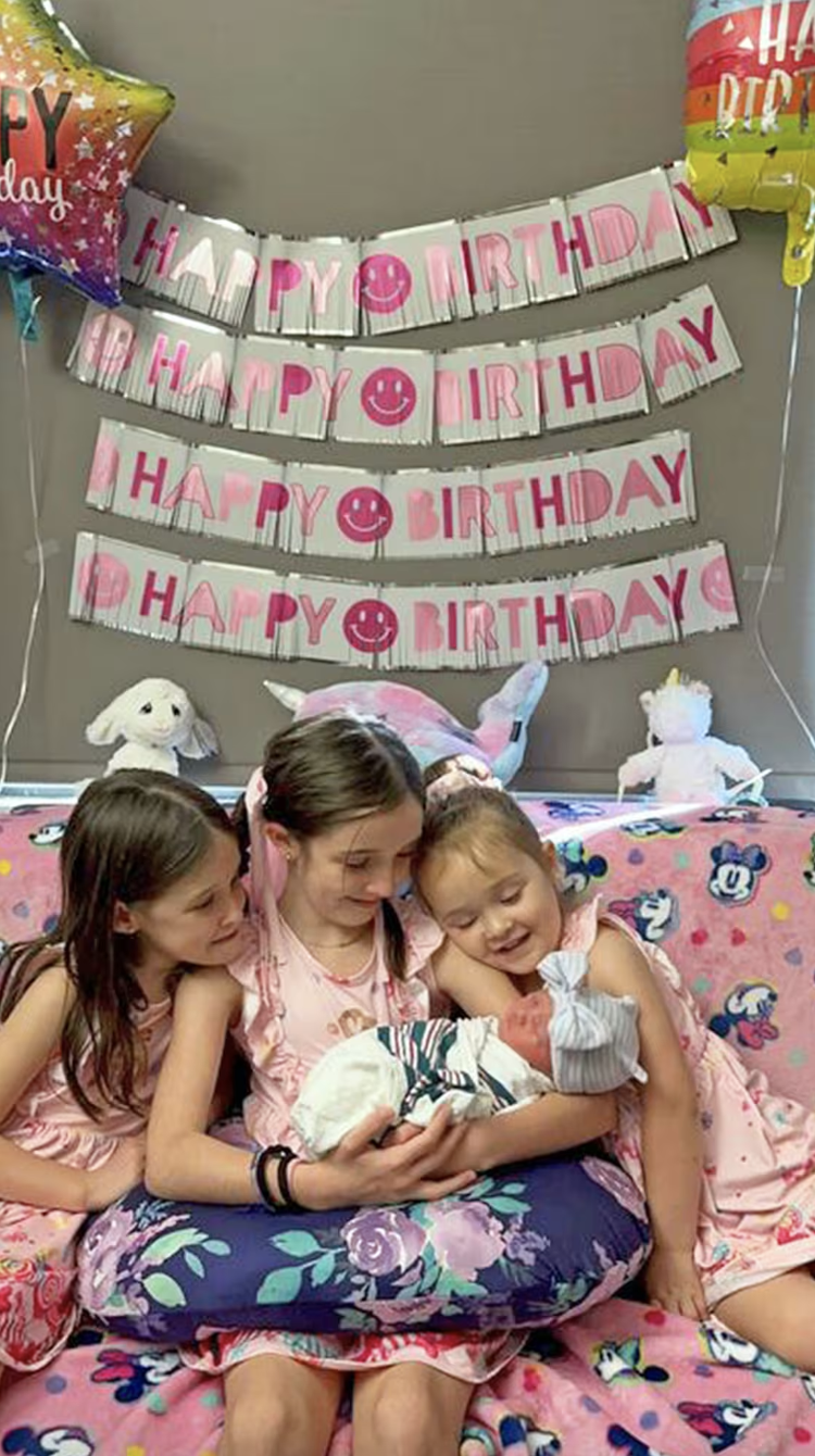 Three older sisters hold their new baby sister.