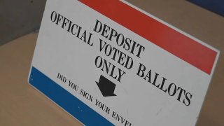 A sign with a red bar on top and blue bar on the bottom that reads "deposit official voted ballots only"