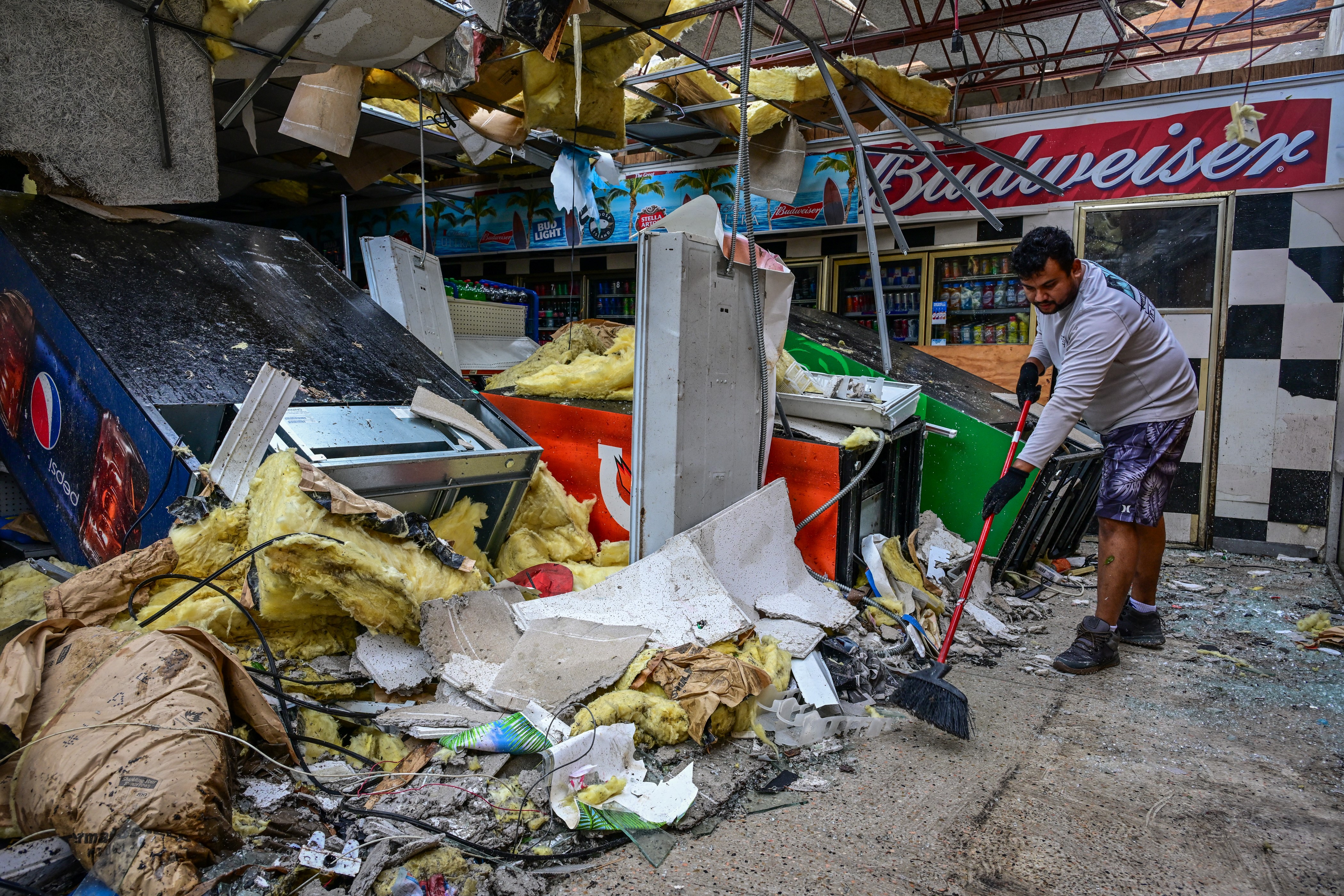 A man cleans debris inside a gas station store in Lakewood Park, Fla, after a tornado hit the area and caused severe damage on Oct. 10, 2024.