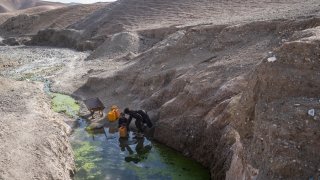 FILE -Two brothers fill canisters with water from a stagnant pool about 3 kilometers (2 miles) from their home in Kamar Kalagh village outside Herat, Afghanistan, Friday, Nov. 26, 2021.