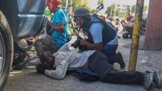 Journalists take cover from the exchange of gunfire between gangs and police in Port-au-Prince, Haiti, Monday, Nov. 11, 2024. (AP Photo/Odelyn Joseph)