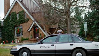 FILE - A police officer sits in her cruiser, Jan. 3, 1997, outside the home in which 6-year-old JonBenet Ramsey was found murdered in Boulder, Colo., on Dec. 26, 1996.