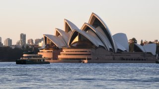 Sydney Harbour taking in the Harbour Bridge, Opera House and ferries at sunrise during the COVID-19 pandemic on April 20, 2020 in Sydney, Australia.