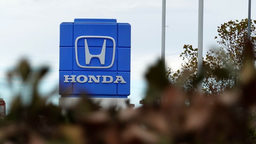 A sign is posted in front of a Honda dealership