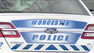 The back of a Worcester Police Department cruiser. The car is white and the text is blue, reading "Worcester police" on the trunk