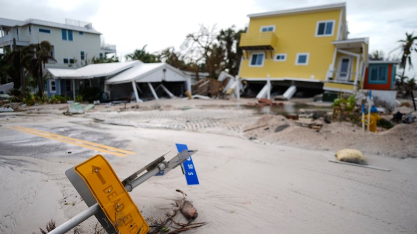 A house sits toppled off its stilts after the passage of Hurricane Milton, alongside an empty lot where a home was swept away by Hurricane Helene, in Bradenton Beach on Anna Maria Island