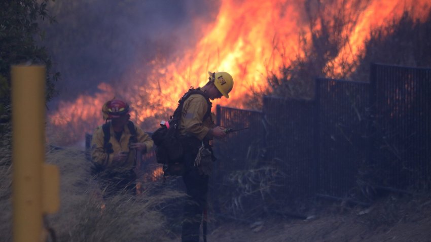 Firefighters work to put out a brush fire burning near homes in Pacific Palisades, California, on January 7, 2025. A fast-moving brushfire in a Los Angeles suburb burned buildings and sparked evacuations Tuesday as “life threatening” winds whipped the region. More than 200 acres (80 hectares) was burning in Pacific Palisades, a upscale spot with multi-million dollar homes in the Santa Monica Mountains, shuttering a key highway and blanketing the area with thick smoke. (Photo by David Swanson / AFP) (Photo by DAVID SWANSON/AFP via Getty Images)