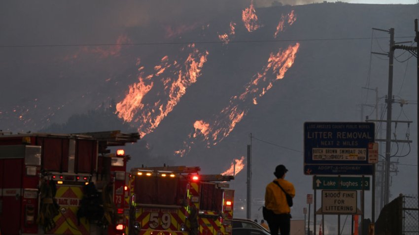 Firefighters watch flames from the Hughes Fire scorch the hillside in Castaic, a neighborhood in northwest Los Angeles County, California, on January 22, 2025.