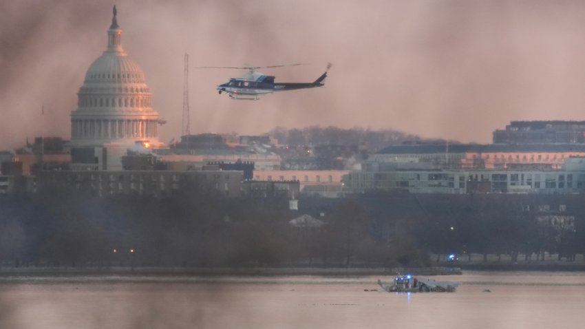 ARLINGTON, VIRGINIA – JANUARY 30: A helicopter flies near the crash site of the American Airlines plane on the Potomac River after the plane crashed on approach to Reagan National Airport on January 30, 2025 in Arlington, Virginia. The American Airlines flight from Wichita, Kansas collided with a military helicopter while approaching Ronald Reagan National Airport. Dozens of people are feared to have died in the midair collision. (Photo by Andrew Harnik/Getty Images)