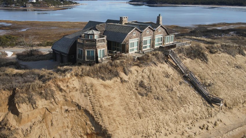 A home sits atop of a sandy bluff overlooking a beach in Wellfleet, Mass, Wednesday, Feb. 2, 2022.