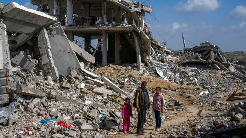 A Palestinian man and two girls stand a mid of the rubble of homes, destroyed by the Israeli army's air and ground offensive against Hamas in in Bureij refugee camp, central Gaza Strip, Monday, Feb. 17, 2025.