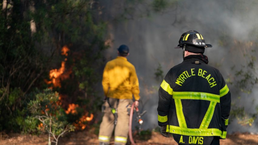 Firefighters attend to a flare-up in the Carolina Forest neighborhood