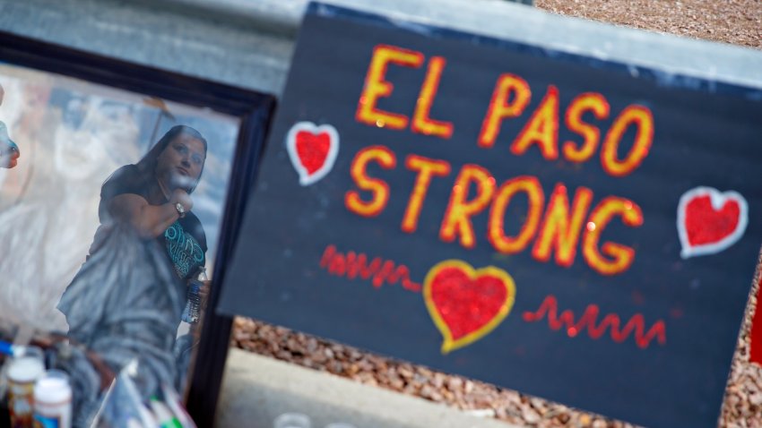 FILE - A woman is reflected in a picture as she looks at a makeshift memorial