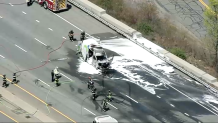 Firefighters around an extinguished vehicle fire on I-95 in Newton, Massachusetts, on Wednesday, April 23, 2025.