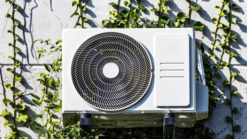 Heat pump on a facade with green plants