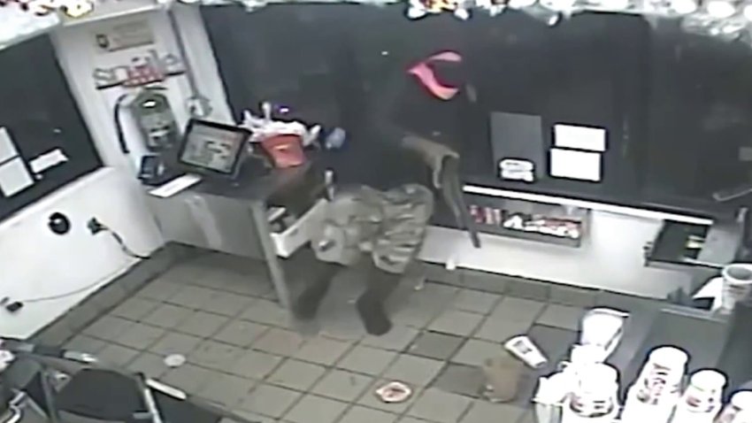 Surveillance video shows how a man climbed through the window of a Checkers in North Miami, shotgun in hand, and allegedly robbed the restaurant as workers hid. 