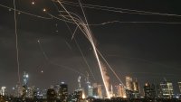 A projectile hit buildings as Israeli Iron Dome air defense system fires to intercept missiles over Tel Aviv, Israel, Friday, June 13, 2025.