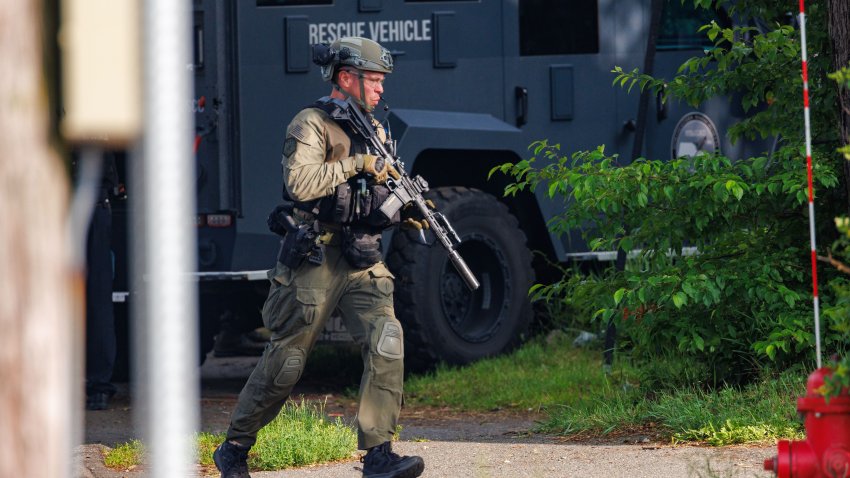 A police officer carrying a long gun and wearing SWAT gear responds to a stabbing in Saugus, Massachusetts, on June 19, 2025.