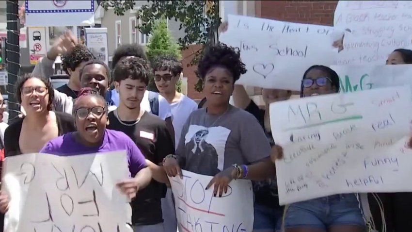 High school students in Woburn hold signs protesting teacher layoffs.